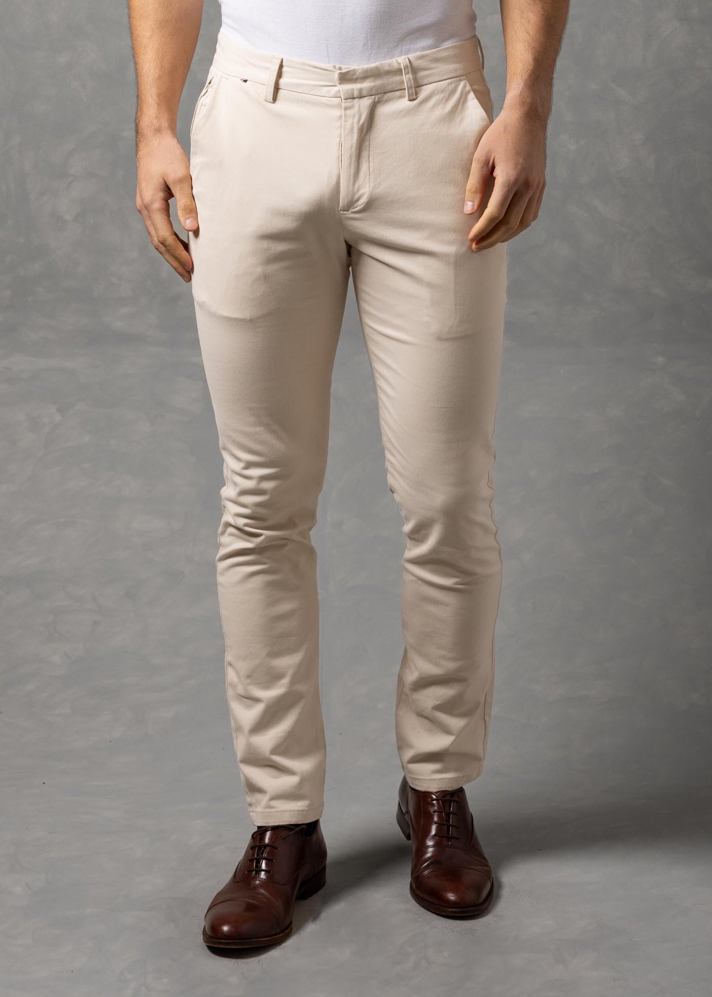 Man wearing a white t-shirt and beige pants against a gray background