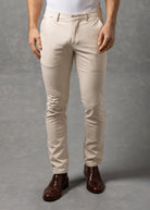 Man wearing a white t-shirt and beige pants against a gray background
