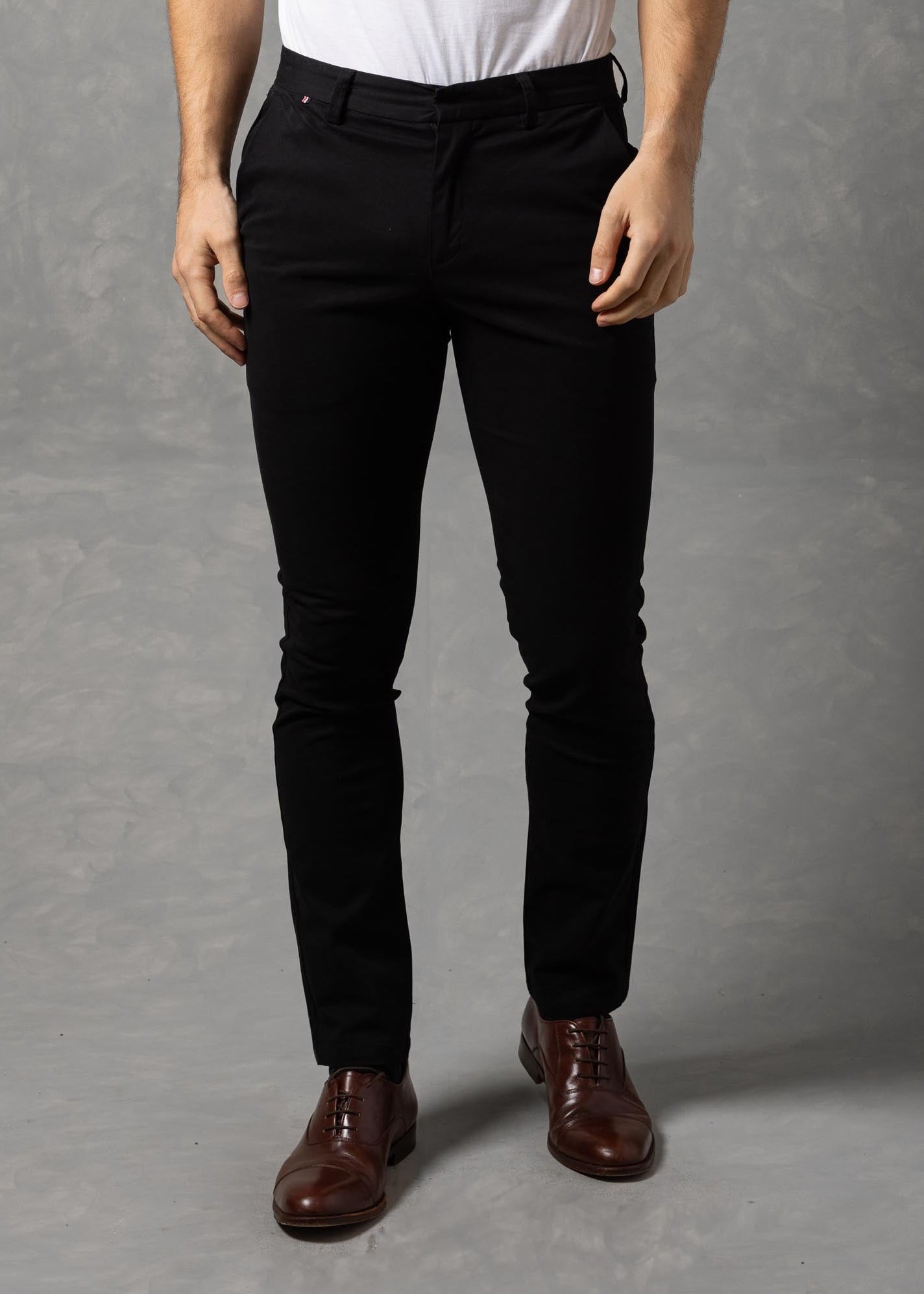 Man wearing a white t-shirt and black pants against a gray background