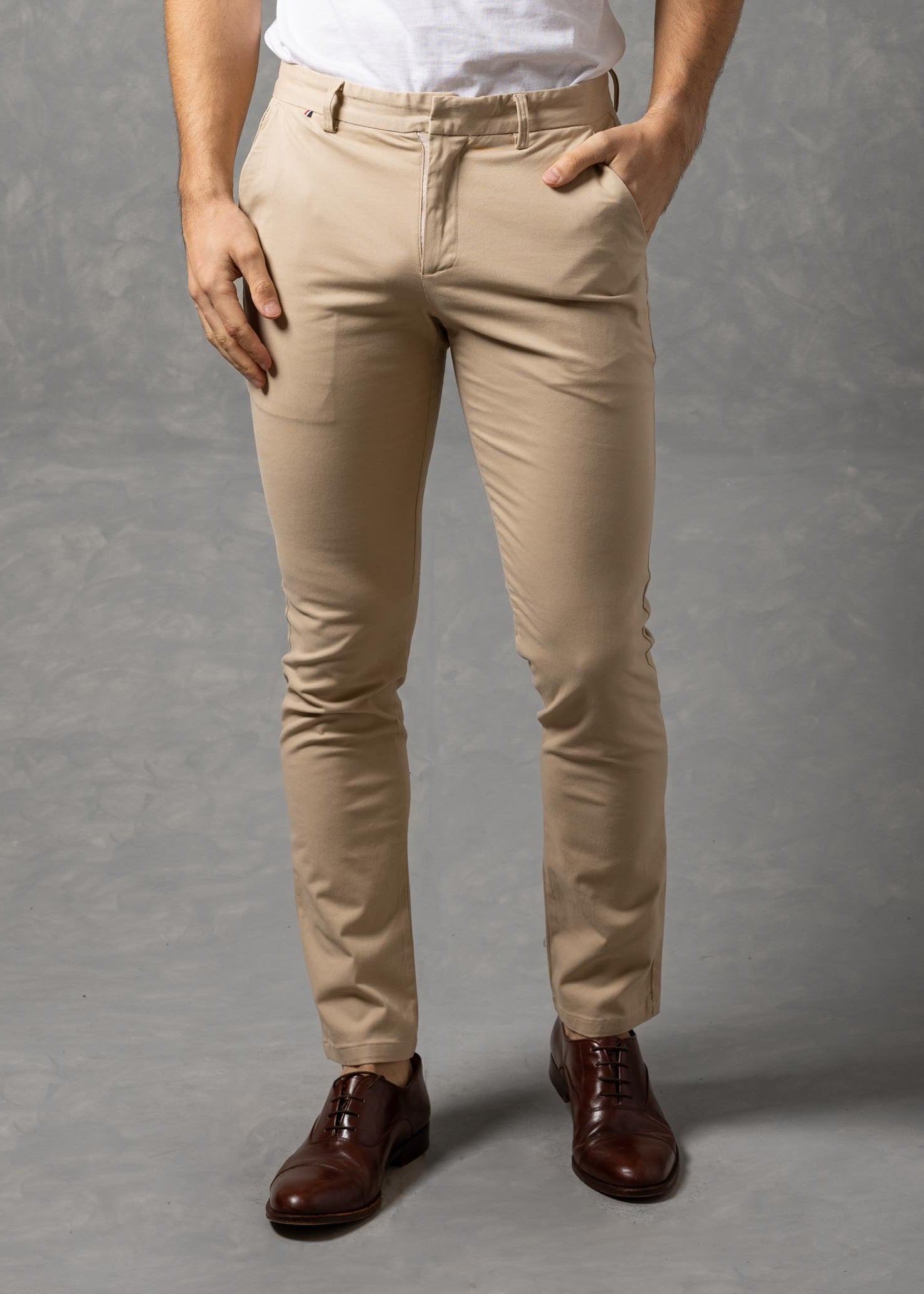 Man wearing a white t-shirt and beige pants against a gray background