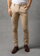 Man wearing a white t-shirt and beige pants against a gray background
