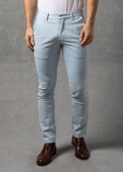 Man wearing a white t-shirt and light blue chino pants against a gray background