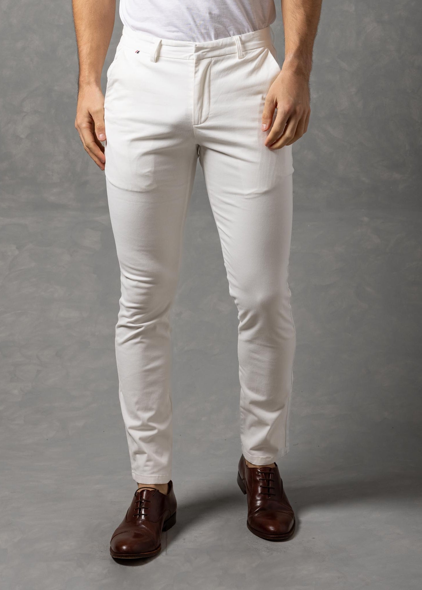 Man wearing a white t-shirt and pants against a gray background