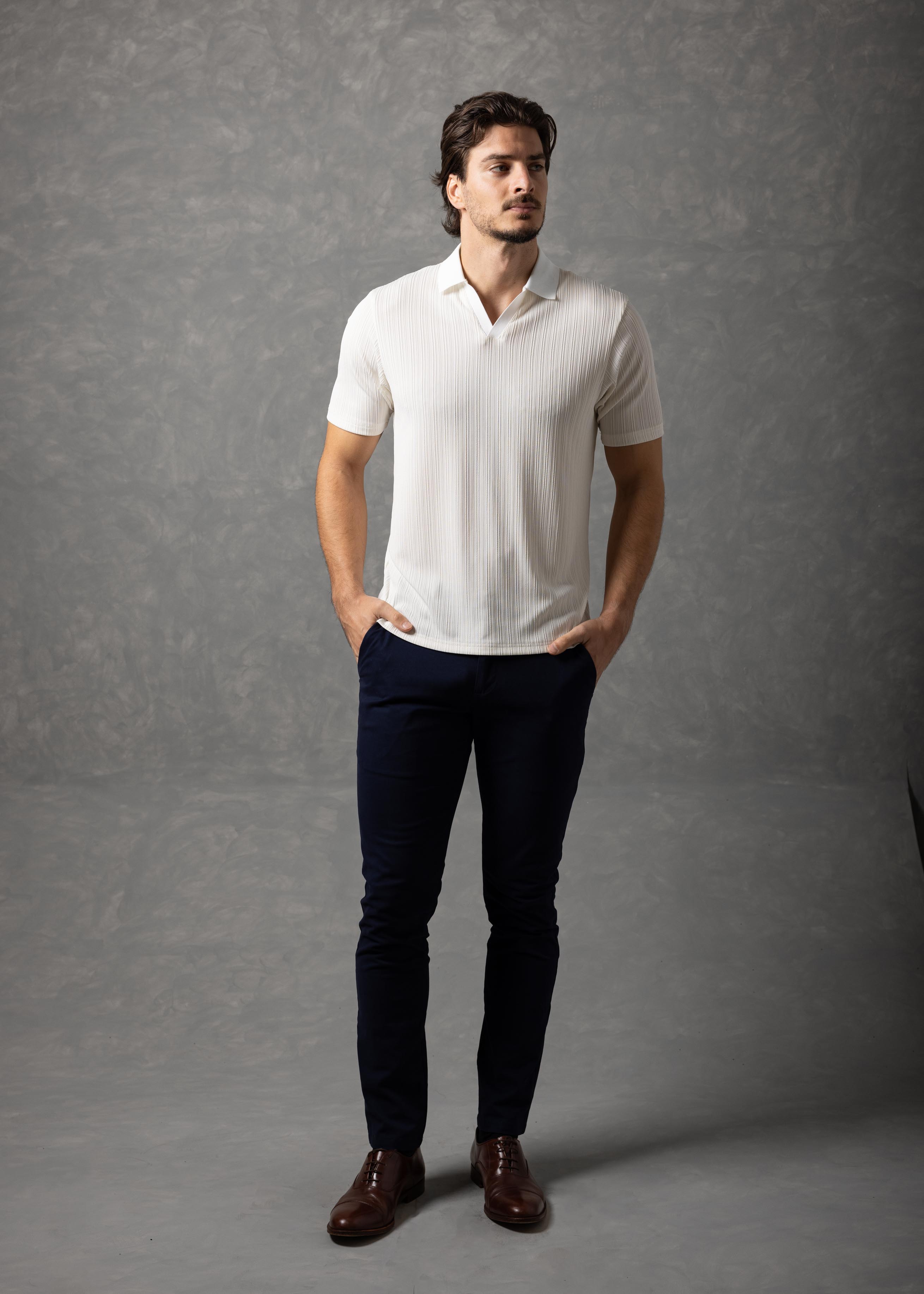 Man wearing a white shirt and dark pants against a gray background
